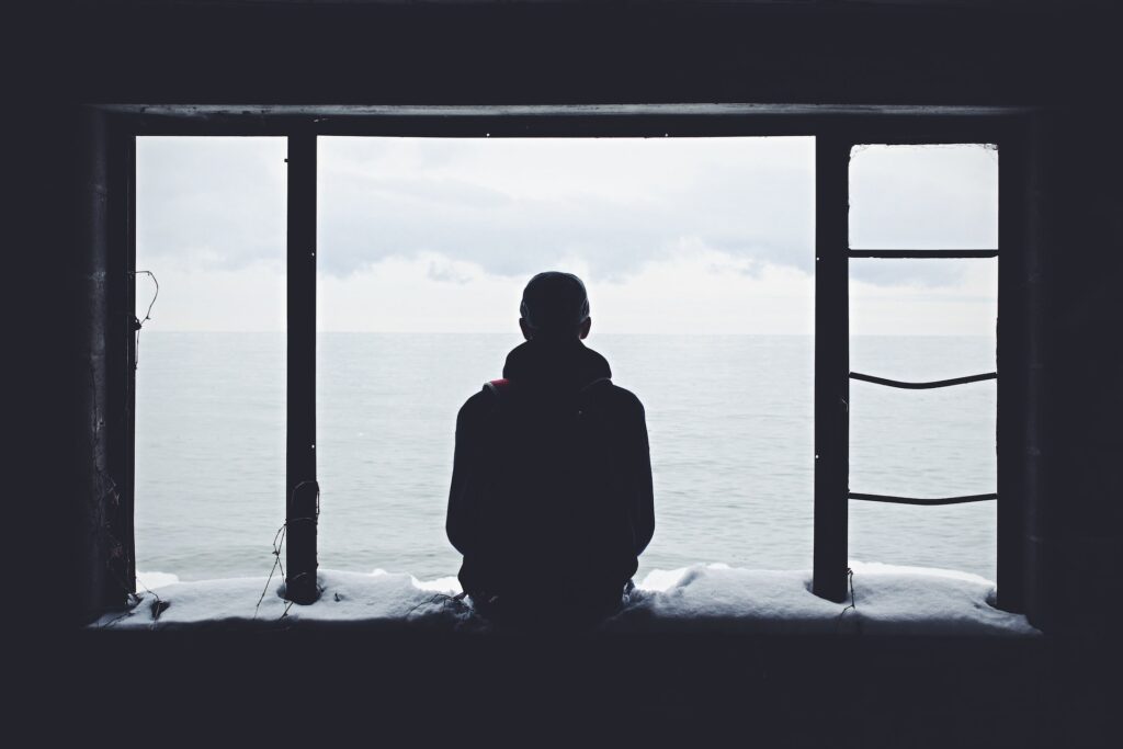 Homem isolado olhando para janela hikikomori