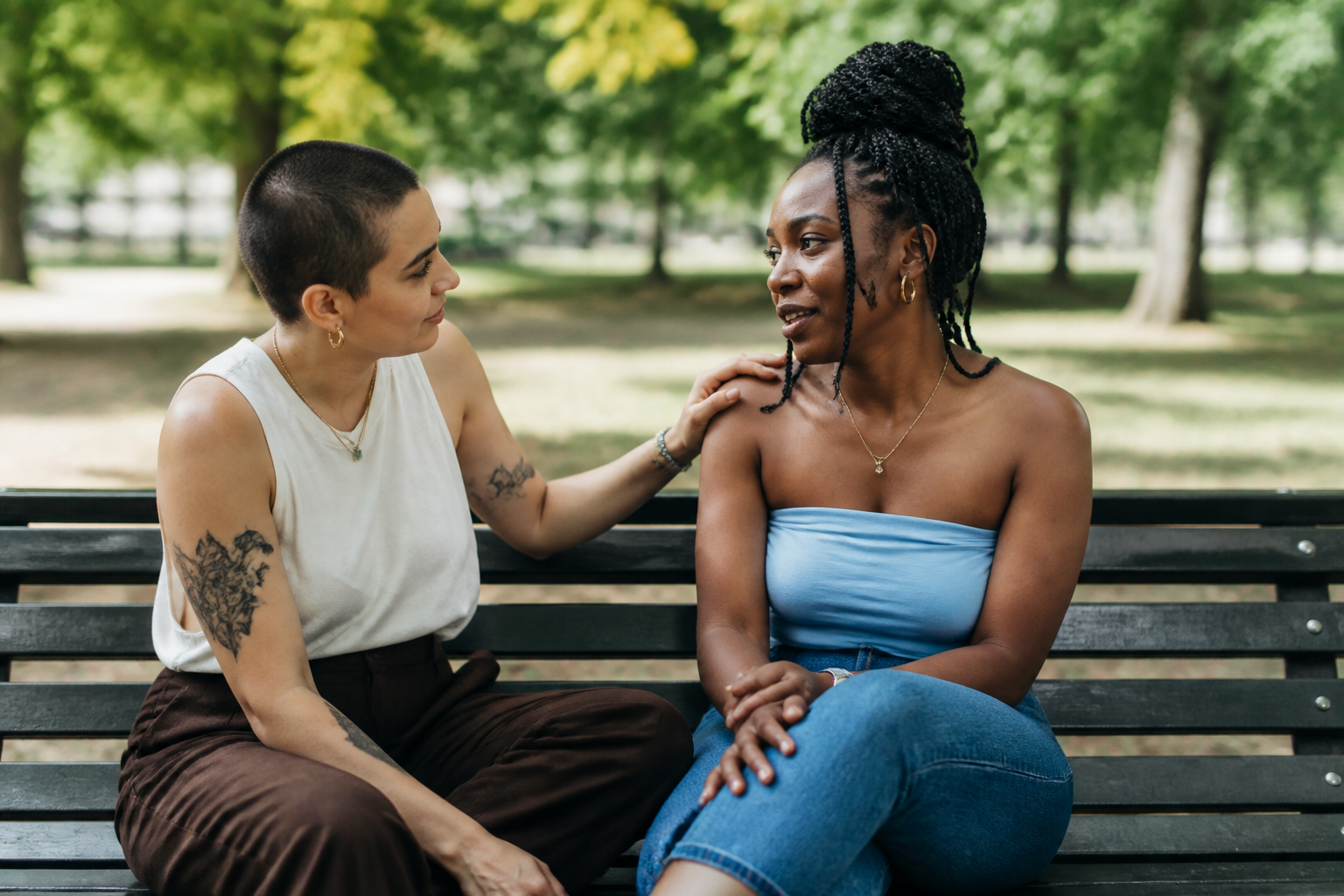 Dois amigos conversam em um parque, demonstrando apoio e carinho um pelo outro.