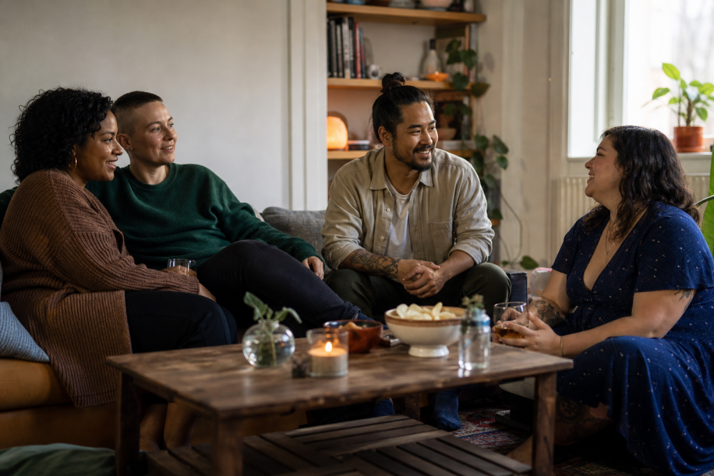 Quatro adultos conversam em uma sala acolhedora, reunidos em um círculo informal.