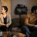 8 sinais de que você pode estar se conformando na relação Um casal sentado em lados opostos do sofá, pensativo e distante em casa.