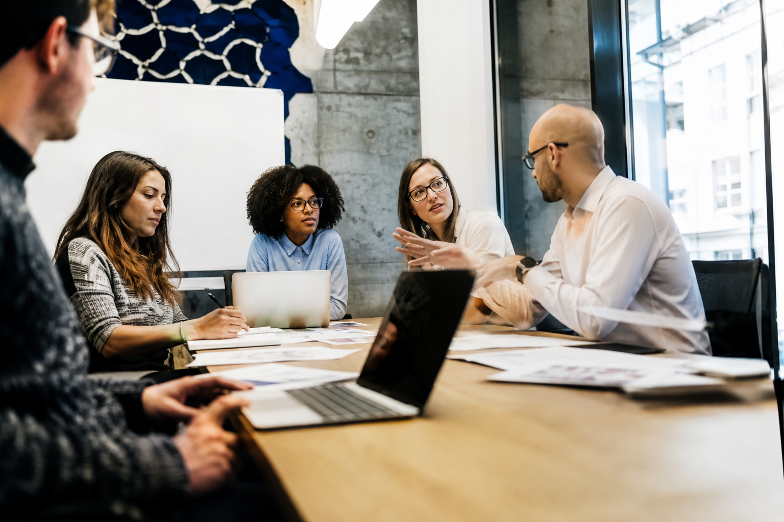 Uma equipe diversa troca ideias ao redor de uma mesa durante uma reunião colaborativa.