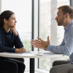 Como lidar com pessoas difíceis sem perder a calma Uma pessoa mantém a calma enquanto conversa com um colega visivelmente irritado em um escritório.